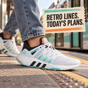 Adidas Equipment GW5836 — Adult in tapered denim steps onto tram platform, foot shape sharp and complete. Vintage ticket-like cream graphic panel only headline no fabricated destinations. Mint/orange accent bars echo sole.