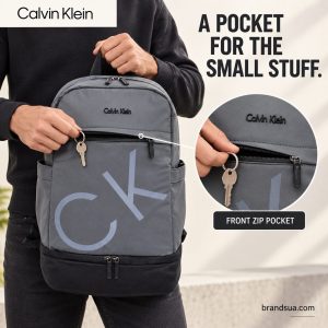 Calvin Klein PackBack — Hand at real pocket shows access without inventing capacity.